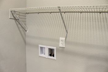 a wire closet organizer hangs on the wall next to two outlets